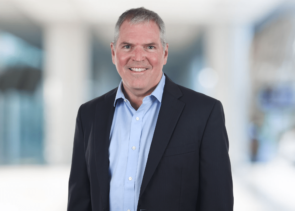 Peter Antkowiak, professional headshot of a smiling man wearing a blue shirt and a suit